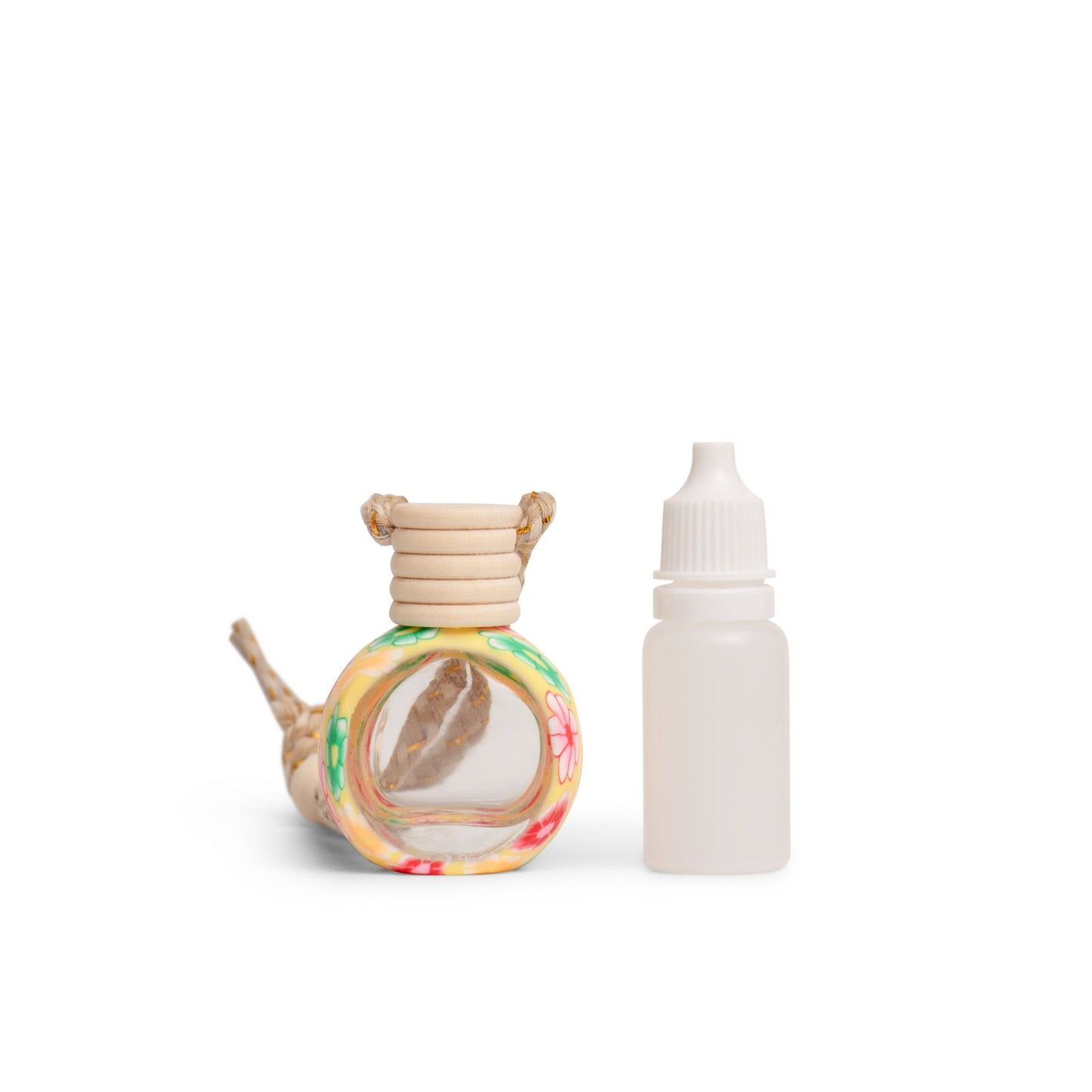 A hanging clay car diffuser with a colorful floral pattern alongside a small white bottle, presumably for fragrance oil.