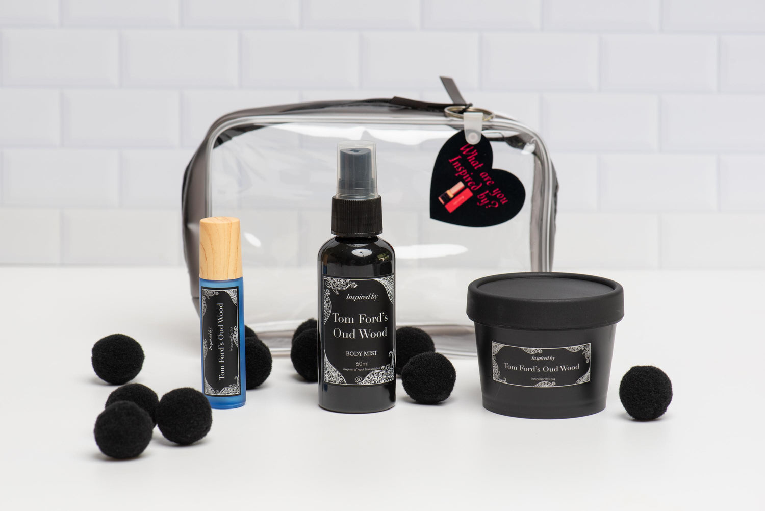 A collection of men's grooming products including a roll-on, body mist, body moisturizer, and a black vinyl cosmetic bag with a keychain that has a red heart design.