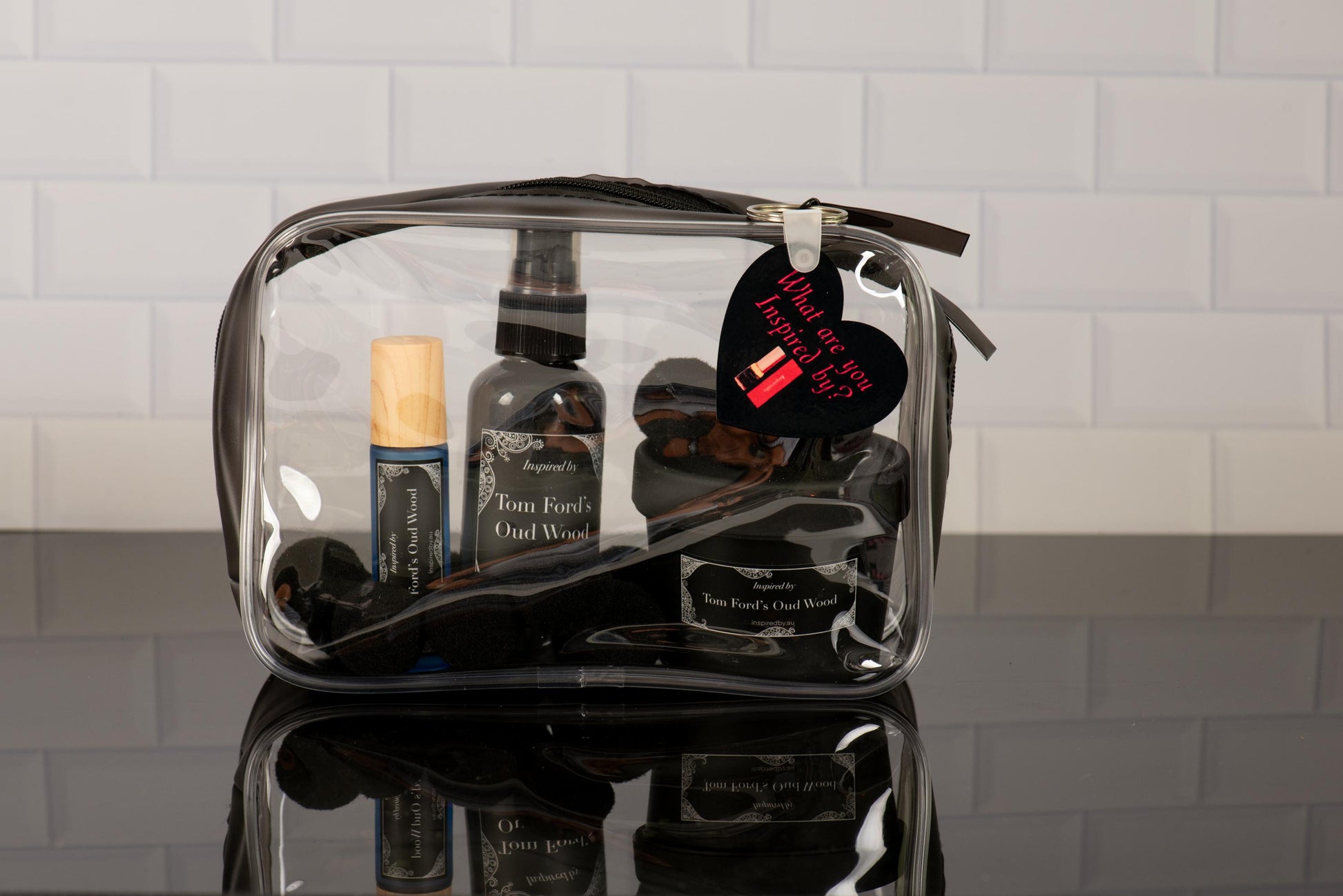 InspiredBy designer-inspired perfume oil collection in travel-friendly clear cosmetic bag featuring various fragrance alternatives and beauty essentials