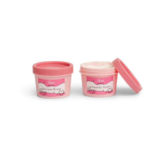 Two open containers of body moisturizer with pink lids, one labeled for men and the other for women.
